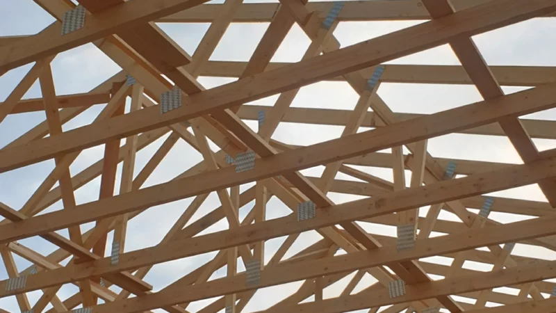 Vue intérieure verticale d’une charpente en fermettes bois sur une maison neuve.