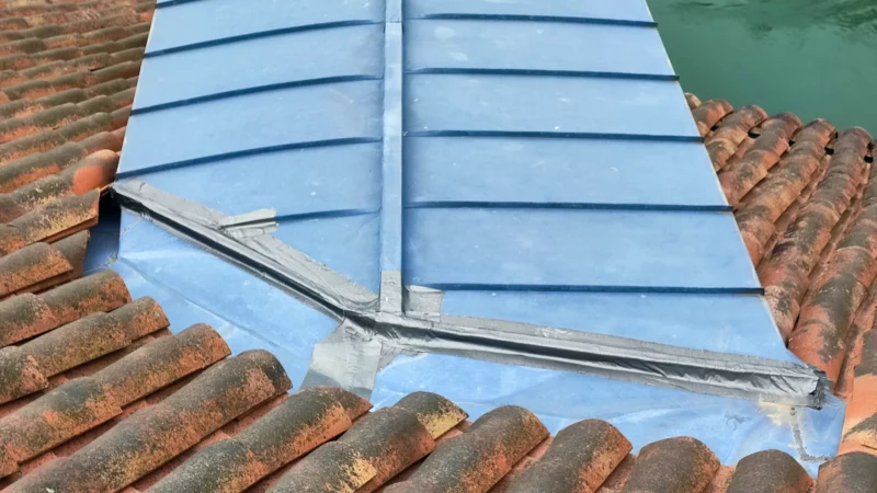 Détail des raccords en zinc entre une couverture métallique et une toiture en tuiles.