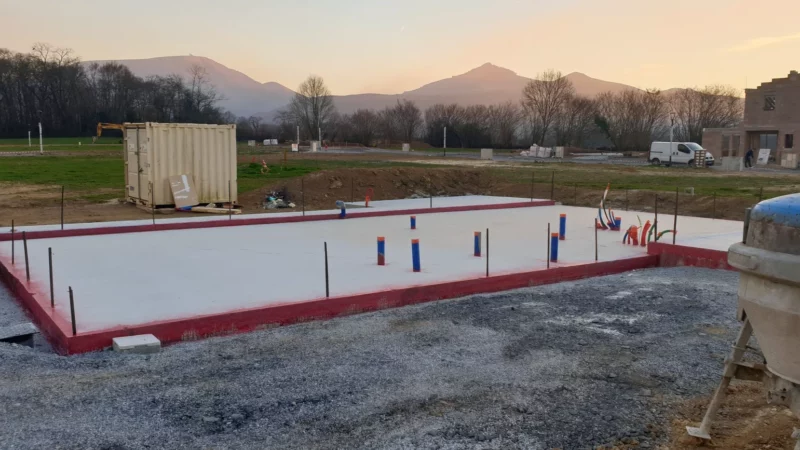 Dalle béton d’une maison neuve avec réseaux et armatures en attente.