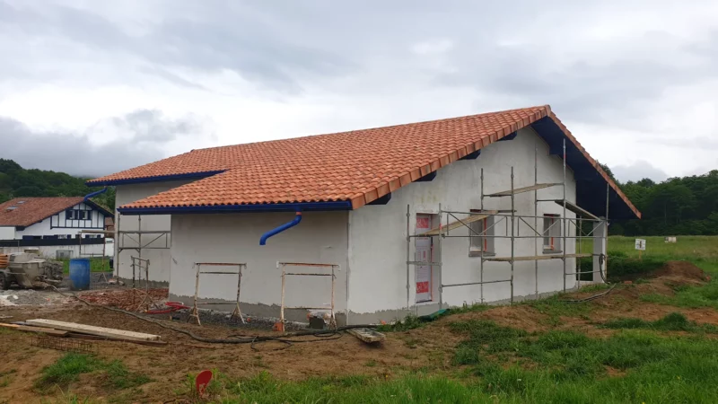 Maison neuve avec enduit de façade en cours d’application autour des échafaudages.