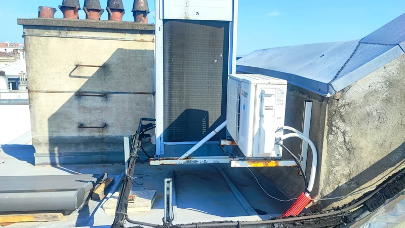 Équipements de climatisation installés sur une toiture en zinc.