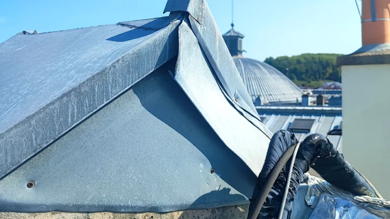 Détail d'un faîtage en zinc déformé sur un ouvrage de toiture.