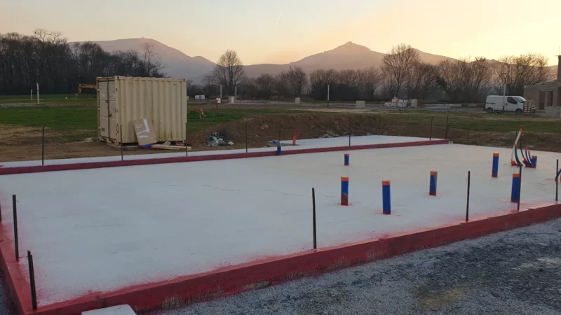 Fondations et dalle béton d’une maison neuve avec réseaux techniques en attente.