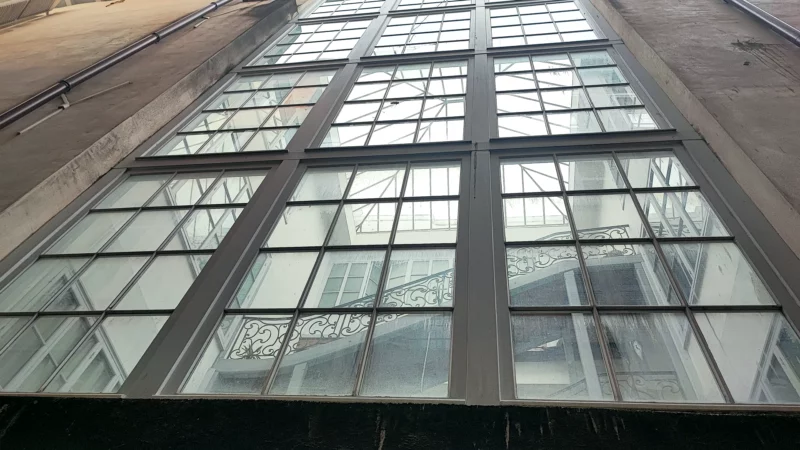 Grande façade vitrée à structure bois dans la cour intérieure de l'immeuble.