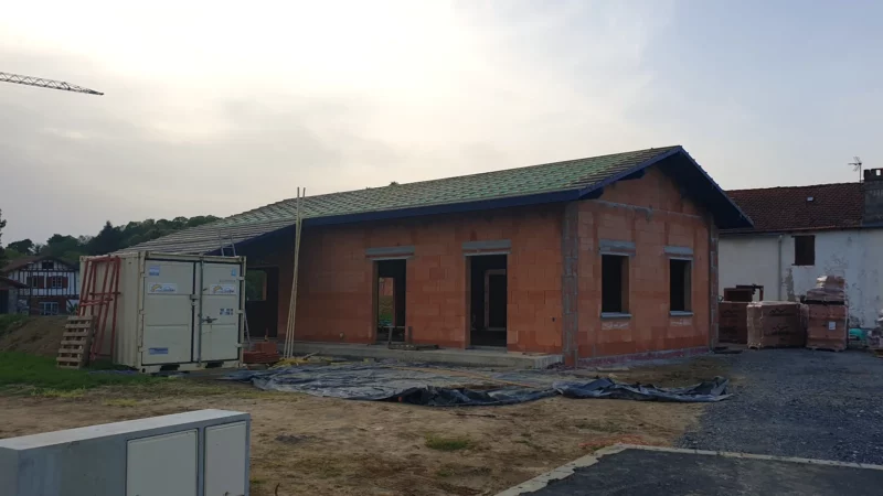 Vue générale du gros œuvre d’une maison neuve avec toiture en cours de réalisation.