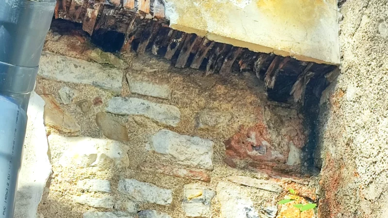 Assemblage ancien en bois, briques et maçonnerie dans une cour intérieure.