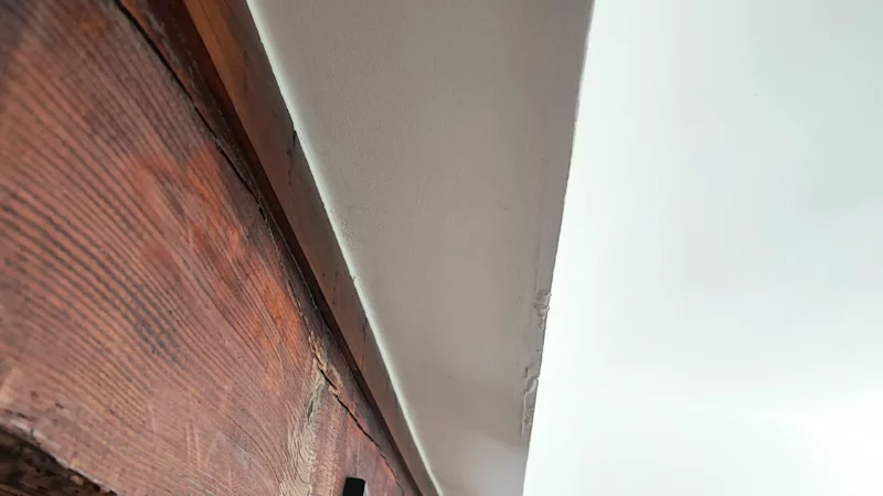 Poutre en bois étayée sous un plafond dans un local intérieur.