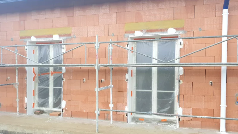 Menuiseries protégées et échafaudage avant l’application de l’enduit sur une maison neuve.