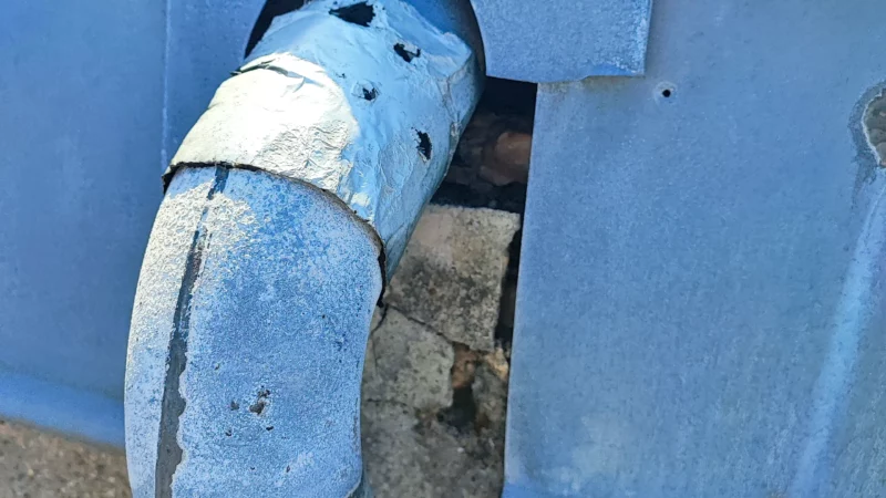 Raccord d'une descente d'eaux pluviales à travers un habillage en zinc.