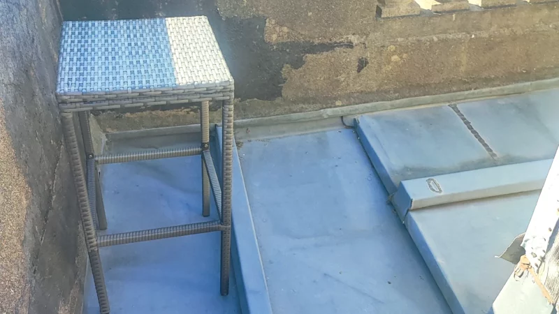 Petite terrasse en zinc bordée par une balustrade ancienne en pierre.